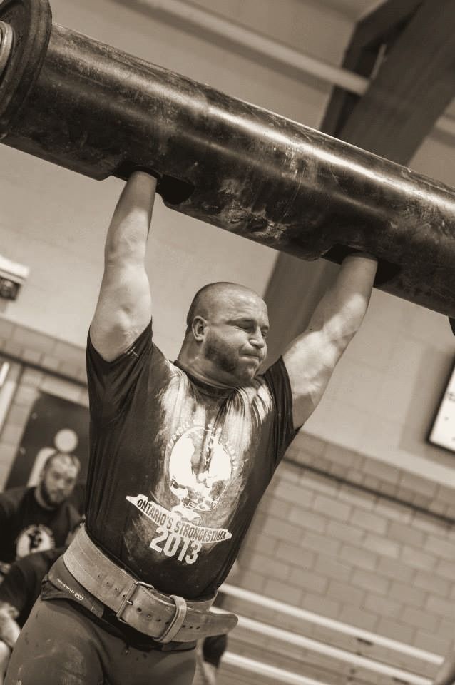 Craig Bongelli pressing a log overhead in strongman competition